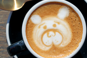 Latte art, drawing of the bearâ€™s face, coffee art made by barista on wooden background table, view from above or top. Close up.