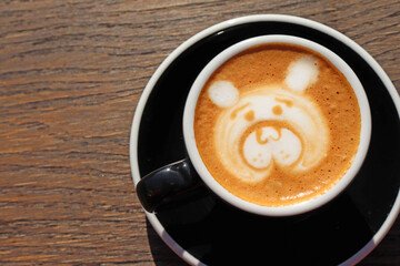 Latte art, drawing of the bear’s face, coffee art made by barista on wooden background table, view from above or top. Copy space for text on the left side. 