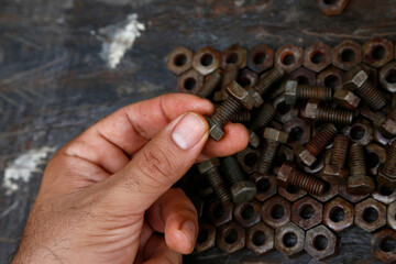 Hands of a mechanic or worker. Man working with rusty nuts and bolts. Manual work table. Oil dirty hands. Employee. Worker. Close up. Nut and bolt insert.