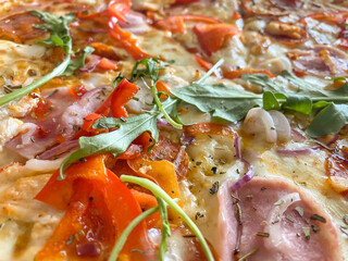 An idea for a pizzeria. Delicious pizza according to the Italian recipe. Close-up of pizza, side view. Pizza with lots of mozzarella, salami, sweet pepper, chicken, herbs and seasonings.