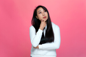 Asian pensive young girl looking aside touch chin lost on thoughts thinking planning business decision solving problem