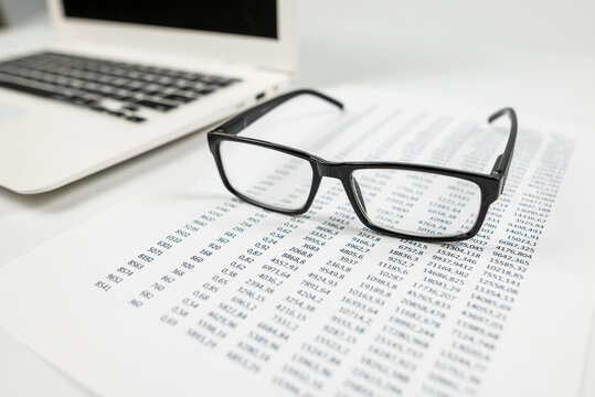 laptop glasses and numbers on paper.