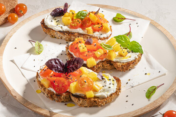 Italian bruschettas with roasted tomatoes, cream cheese, pineapple slices and herbs on a kitchen countertop. Prepared to serve