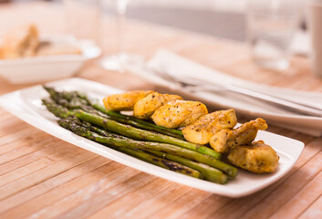 cooked dish. Chicken nuggets with green asparagus on plate
