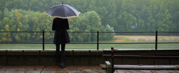 Beautiful girl with umbrella walking outdoor on a rainy misty autumn day