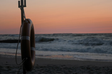 Close-up of a life preserver rippling in the wind against the choppy cold sea at beautiful sunset