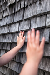 Feel the old rough surface with your hand. Child touches and feels wood. Wooden shingles. Alte raue Oberfläche mit Hand spüren. Kind tastet und spürt Holz. Traditionelle Schindel aus Holz.