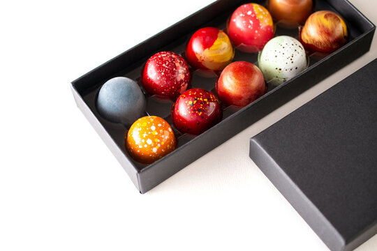 Open gift box with assortment of homemade chocolate bonbons. Modern hand painted chocolate candy. Product concept for chocolatier