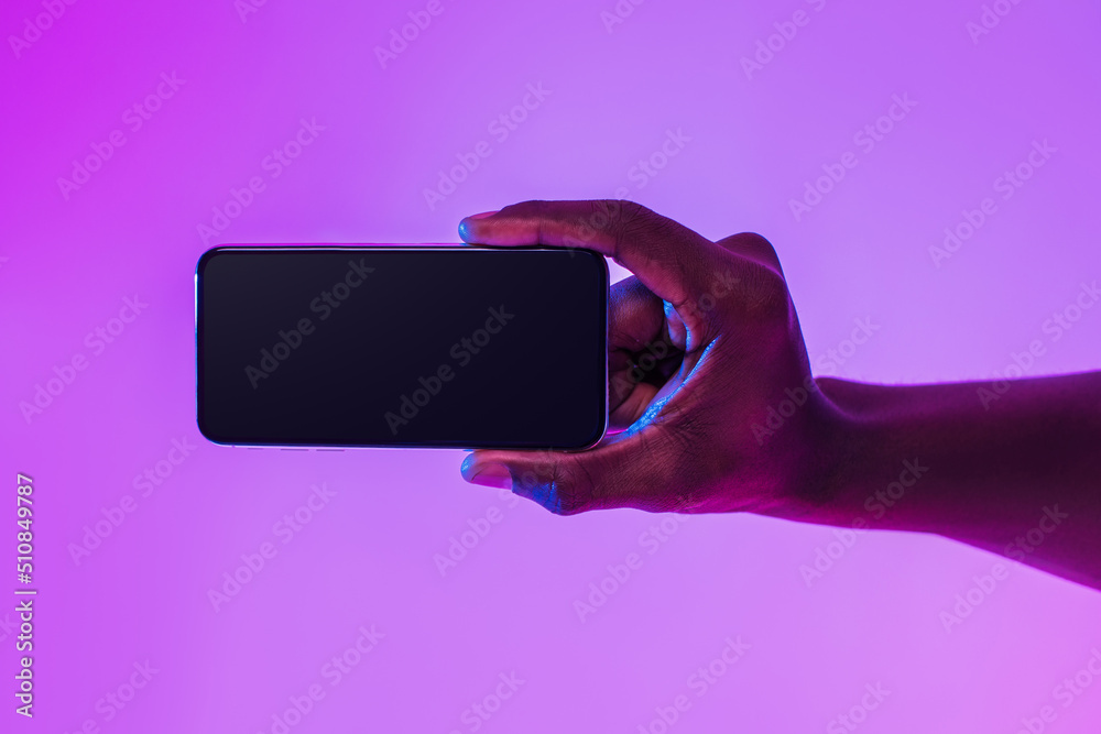 Poster closeup of young black guy holding smartphone with empty screen, showing space for mobile app or web