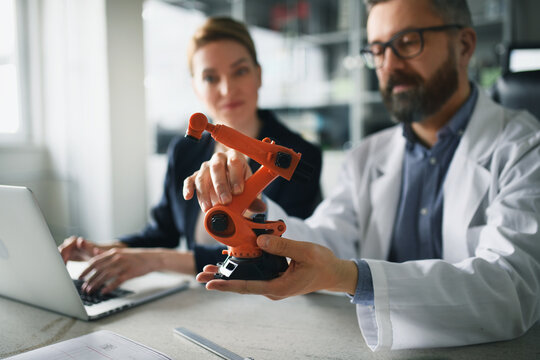 Robotics engineers working on laptop and desinging modern robotic arm in laboratory.