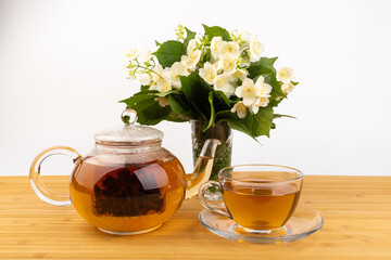 Composition with cup of jasmine tea and flowers on light background
