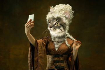 Beautiful female model like medieval person in vintage clothing headed by cat head isolated on dark...