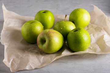 Several fresh ripe green apples lie on parchment paper. Selective focus.