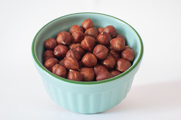 Hazelnuts without shells, turquoise color bowl filled with nuts, nutritious snack, ready for eating or use in cooking recipes, ingredient, organic.
