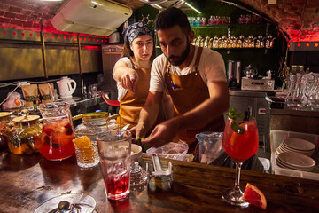 Male and female bartenders are making cocktails