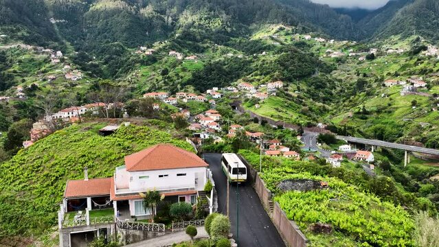 Local bus navigates scenic road in mountainous terrain, Madeira; aerial