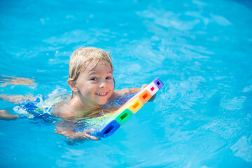 Cute toddler boy, swimming in pool with board