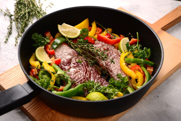 roasted meat with vegetables on frying pan