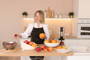 A woman in an apron and fresh fruits lemons, strawberries, apples, coconut, oranges, grapefruits