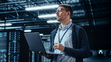 Successful Data Center IT Specialist Using Laptop Computer. Server Farm Cloud Computing Facility...