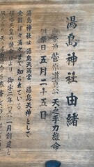 Wooden sign at front of &ldquo;Yushima Tenjin&rdquo;, the ancient historic shrine established all the way in year 458, it is written in Japanese characters the origin of its establishment.  Shot taken 2022/6/14