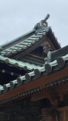 Fototapeta na wymiar Delicate artistic detail of Japanese shrine “Yushima Tenmangu” established year 458, 5 petals of sakura as their “Kamon (family crest)” embedded on the rooftop horn (Toribusuma), photo on 2022/6/14