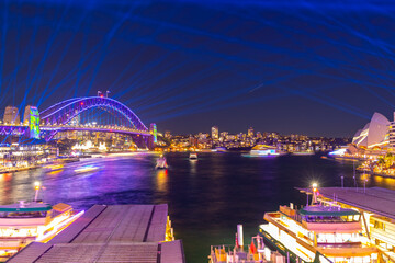 Fototapeta na wymiar Colourful Light show at night on Sydney Harbour NSW Australia. The bridge illuminated with lasers and neon coloured lights 