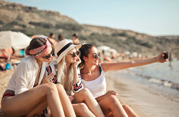 Fototapeta three girls on the beach take a selfie obraz