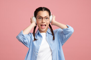 Cute Asian girl is wearing headphone and standing on pink background with happy face, blank copy space for your advertising content.