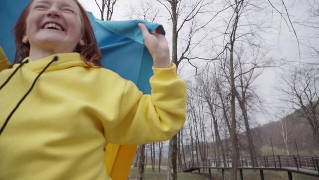 The girl walks in the park with the flag of Ukraine. Ukrainka is happy for Ukraine. Ukrainian national symbols.
