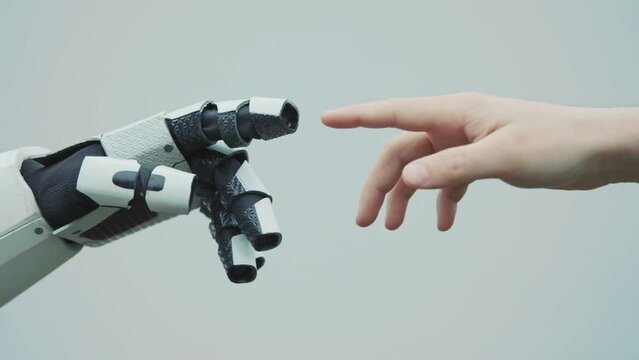 Footage of human-like robot and human touching fingers on white background of studio. Intelligent white machine. Creator and invention. Artificial Intelligence. Future lifestyle concept. Close-up shot