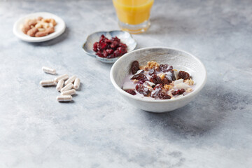 Bowl of granola with yogurt, nuts, cranberry and cocoanut. Sport supplements ( carnitine capsules ) in background. Bright stone  background. Copy space. 