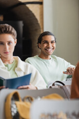 young african american man smiling during lecture in university near blurred classmate.