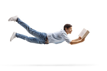 Full length profile shot of a casual young man flying and reading a book