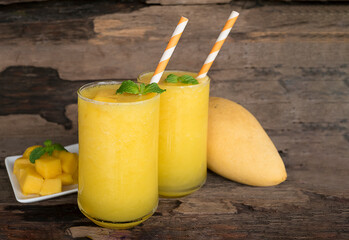 Fototapeta premium Mango juice fruit smoothies yogurt drink yellow healthy delicious taste in a glass slush for weight loss on wooden background.