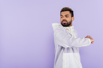 bearded african american sportsman in sportswear warming up isolated on purple.