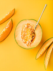 Exotic cantaloupe melon and slices on marigold coloured backdrop. Ripe tropical fruit background. Idea of summer season food trend. Food photography. Flat lay, copy space. - obrazy, fototapety, plakaty