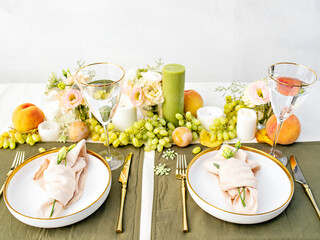 Festive table setting for two person. Restaurant, wedding, party decorated with flowers, candles, fruits and leaves. Midsummer or autumn mood event, romantic dinner. Florist decorator occupation.