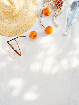 Summer inspired background with straw hat, female sunglasses and reusable shopper bag with fruits on towel. Minimalist vacation creative still life ​for fashion blog, web, social media, stories.