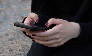 female hands holding a smartphone with a blank screen to copy a text message or informational content, a woman reading a message on a mobile phone in the city in a park among trees