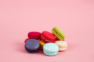 Colourful desserts macaroons on pink background, copy space.