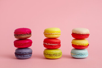 Obraz na płótnie Canvas Three stacks of colourful french macaroons or macaron on pink background, Dessert.