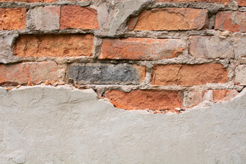 an old dark brown and red brick wall with fallen plaster, rough rusty blocks of masonry technology