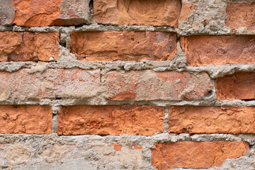 an old dark brown and red brick wall with fallen plaster, rough rusty blocks of masonry technology