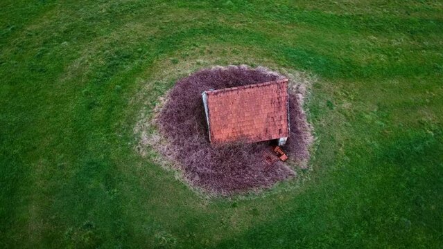Maisonnette au milieu d'un champ d'herbe verte. Construction isol&eacute; en pleine nature.