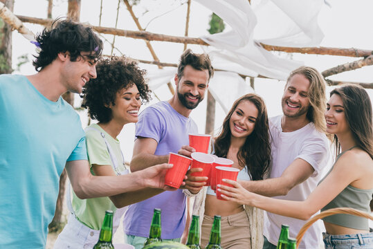 Photo of pretty excited young people wear casual clothes rising cups drinking beer outside countryside
