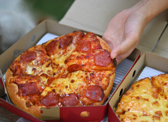 People Hands Taking Slices of Pizza delivery plate . Pizza and food concept. Close up focus on middle pizza. happy outdoor party background time.