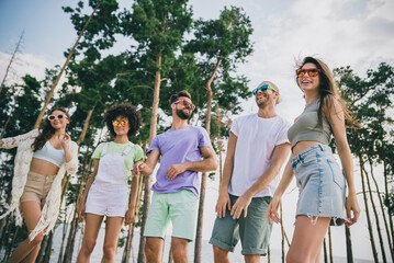 Photo of five cheerful carefree friends have fun hanging out forest festival party outdoors