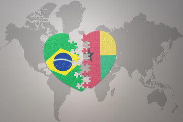 puzzle heart with the national flag of brazil and guinea bissau on a world map background.Concept.