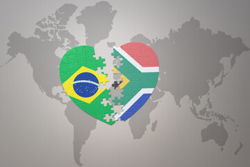 puzzle heart with the national flag of brazil and south africa on a world map background.Concept.